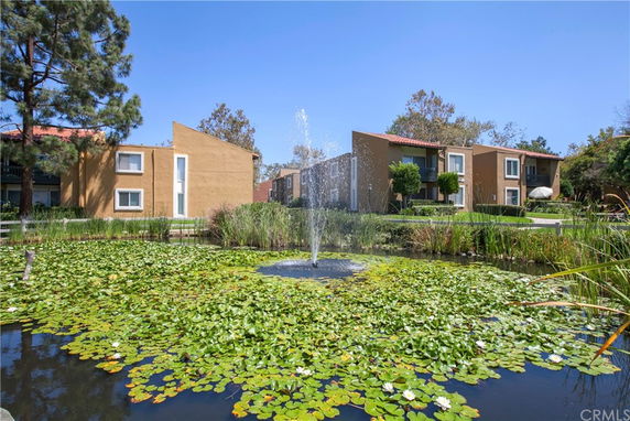 View of residential buildings with a pond and fountain in the foreground.