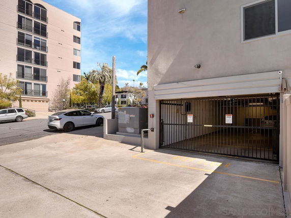 Outdoor parking area with a gated entrance to a building's parking garage.