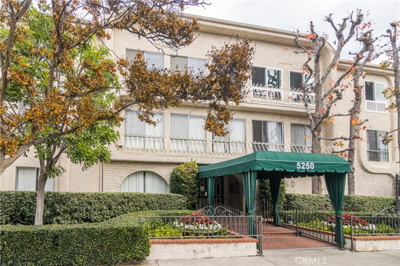 Front view of a multi-story residential building with a green awning over the entrance.