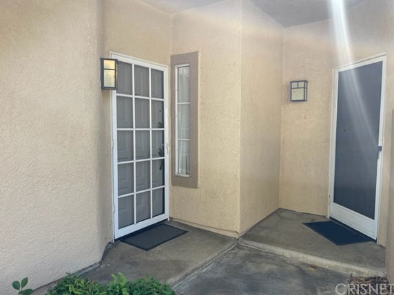 Front entrance of a building with two doors and wall-mounted lights.