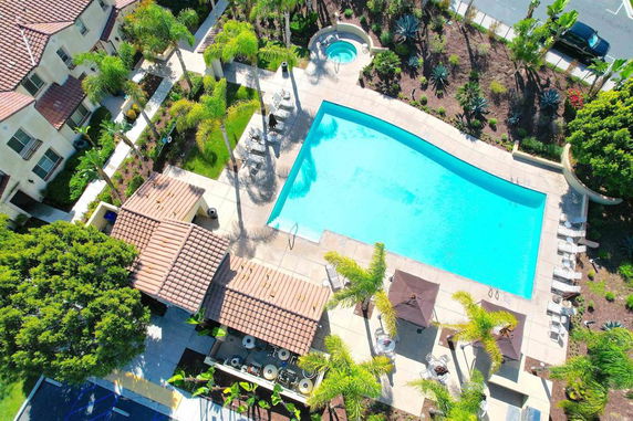 Aerial view of an outdoor swimming pool with surrounding seating and a small adjacent hot tub.