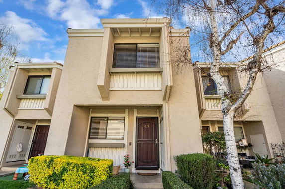 Front view of a two-story townhouse with beige exterior and a brown front door.