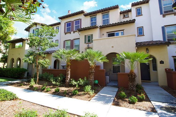 Front view of a multi-story residential building with arched entryways and a garden.