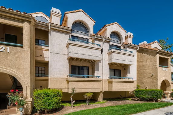 Front view of a multi-story residential building with balconies and arch windows.
