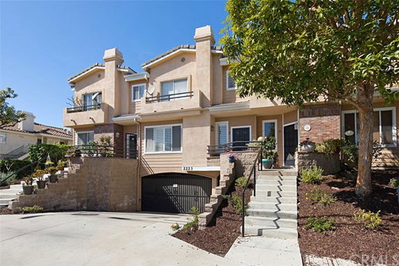 Front view of a multi-story house with a driveway and stairs leading to the entrance.