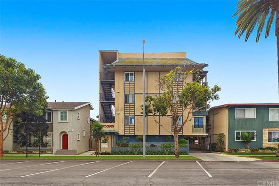 Front view of a multi-story apartment building with a flat roof and exterior staircases.