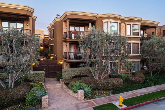 Front view of a multi-story building with balconies and landscaping.