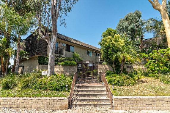 Front view of a two-story house with trees and shrubs in front.