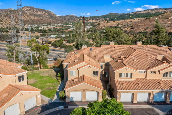 Aerial view of a residential complex with mountainous terrain in the background.