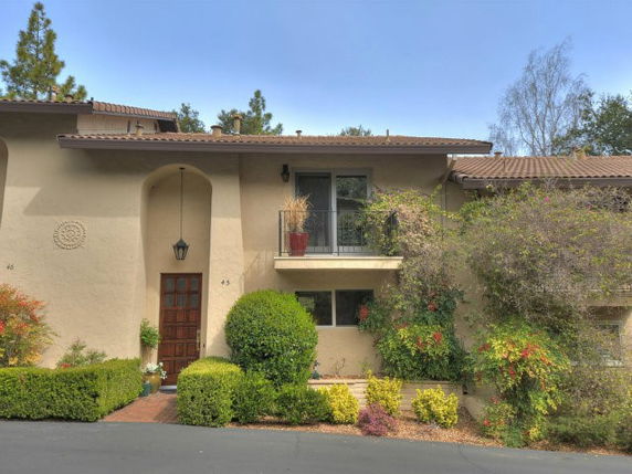 Front view of a two-story house with a balcony and an arched entryway.