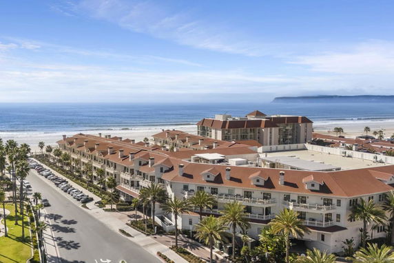 Aerial view of a beachfront building complex with red roofs located near the ocean.