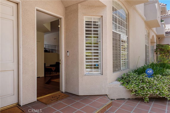 Partial front view of a house with arched windows and tiled entryway.