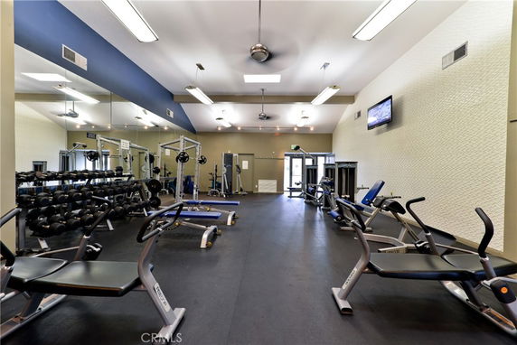 Indoor gym area with workout equipment and mirrors.