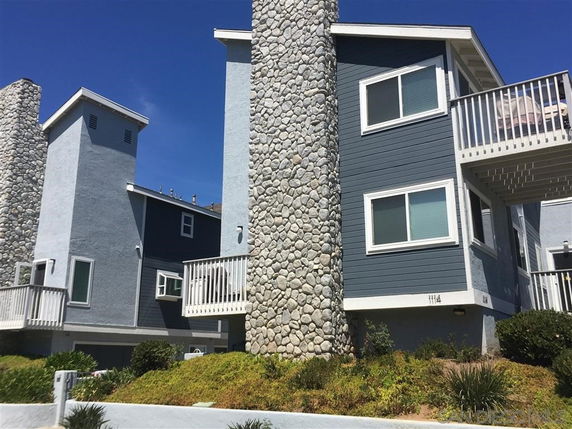 Front view of multi-story houses with stone chimneys and balconies.