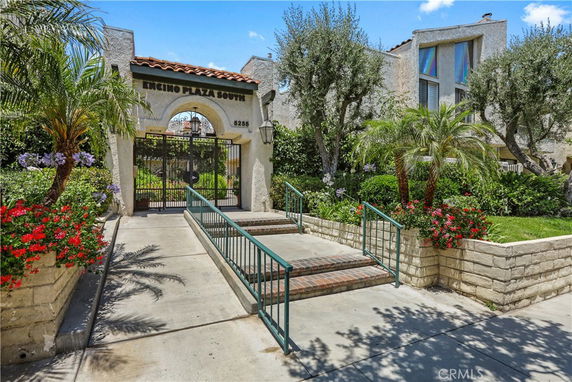 Front view of a gated entrance with a sign reading 'Encino Plaza South' and a pathway leading up to it.