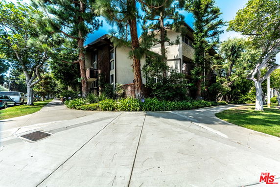 Front view of a multi-story building surrounded by trees and greenery.