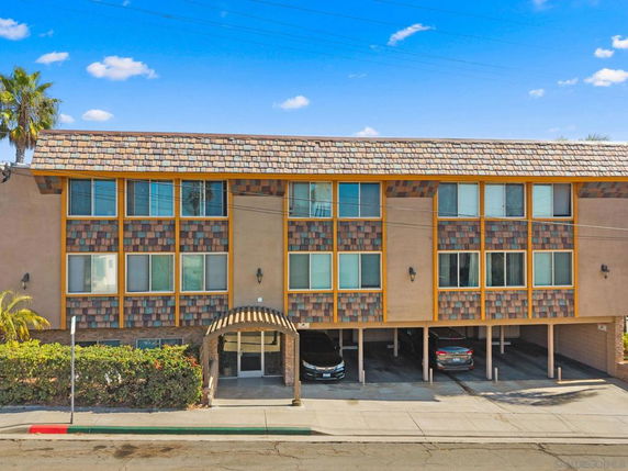 Front view of a multi-story building with a covered parking area.
