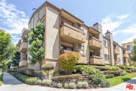 Corner view of a multi-story apartment building with balconies and stone accents.