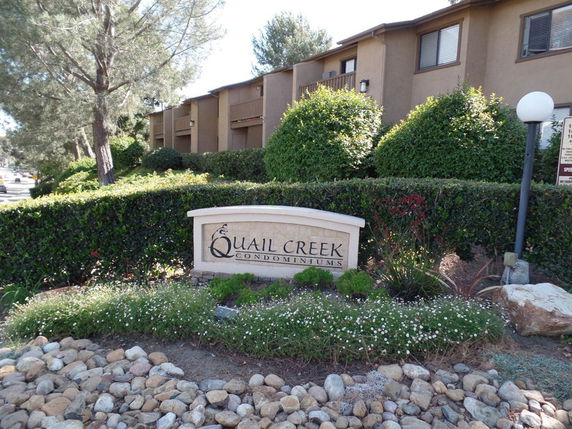 Front view of a condominium complex with a sign reading 'Quail Creek Condominiums'.
