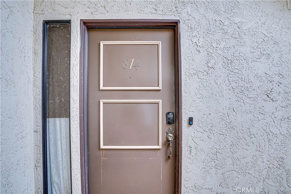 Close-up of a brown front door with the number 814, surrounded by stucco walls.
