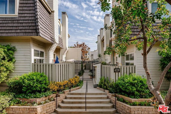 Front view of a residential building with exterior steps and a fenced entrance.
