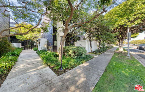 Front view of a multi-story building with a garden path and trees.