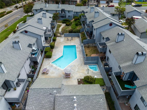 Aerial view of a residential complex with a central swimming pool and surrounding buildings.