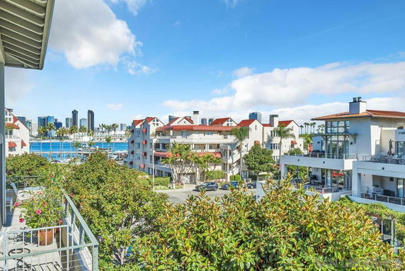 View of residential buildings with red roofs and a city skyline in the background.