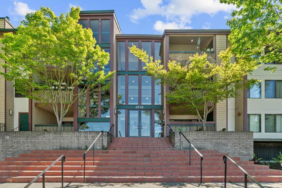 Front view of a multi-story building with large windows and stairway entrance.