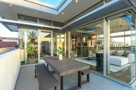 Rooftop view of a modern house with large glass windows and a patio area.
