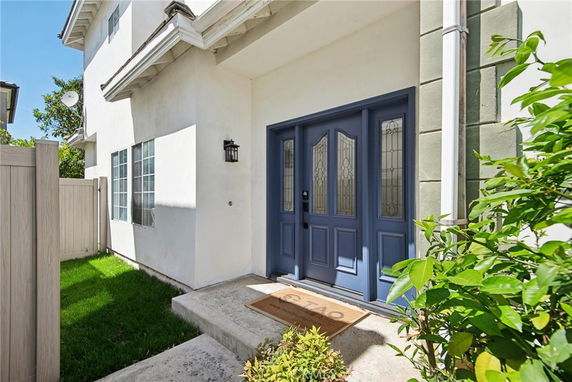 Front view of a two-story house with a blue entrance door and adjacent windows.