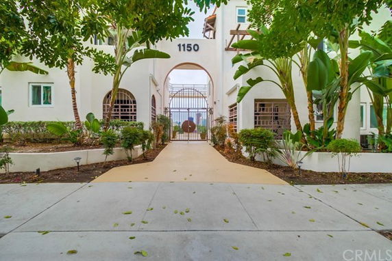 Front view of a multi-story building with an arched entrance and surrounding greenery.