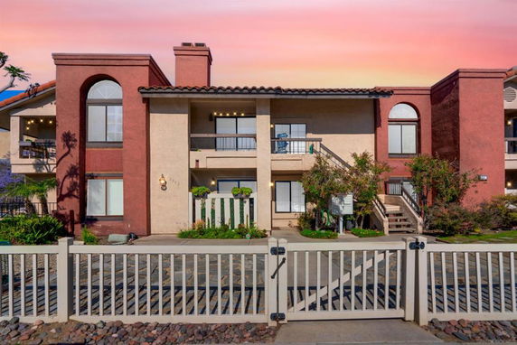 Front view of a two-story house with a balcony and arched windows.