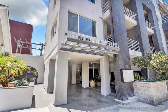 Front view of a modern multi-story building with a prominent entrance and balconies.