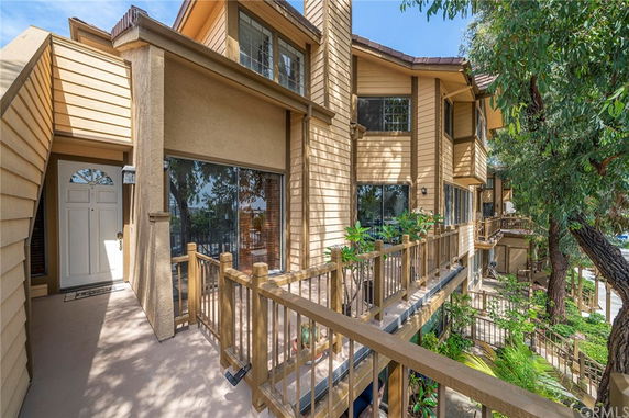 Front view of a multi-story townhouse with large windows and a wooden railing.