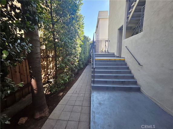 Side view of a building with exterior stairs and a pathway alongside.