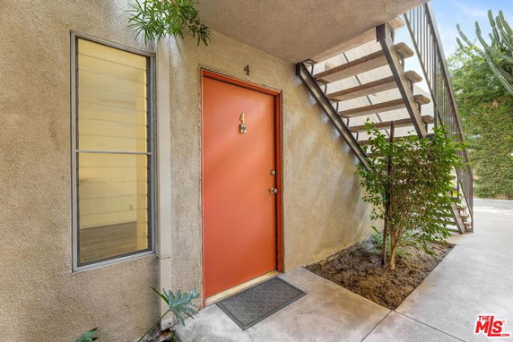 Exterior entrance of a building with a numbered red door and an adjacent staircase.