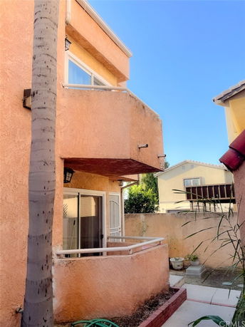 Exterior view of a two-story house with stucco walls and a small balcony.