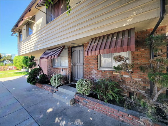 Front view of a house with brick facade and window awnings.
