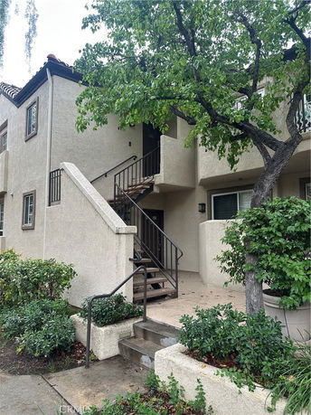 Front view of a two-story residential building with an external staircase and stucco exterior.
