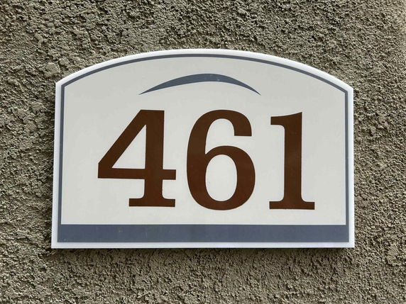 Close-up of a house number '461' on a textured wall.