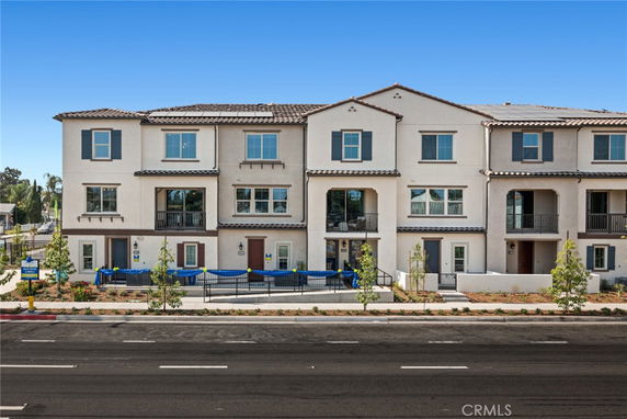 Front view of a multi-level residential building with a symmetrical design and balconies.