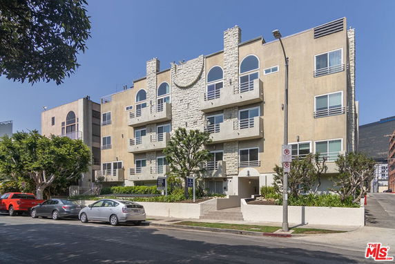 Front view of a multi-story residential building with balconies and stone accents.