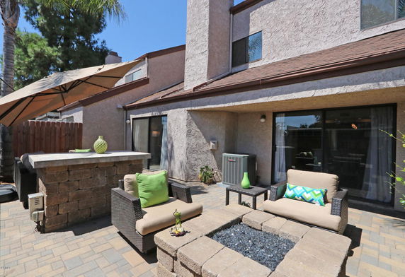Front view of a two-story house with a patio and outdoor seating area.