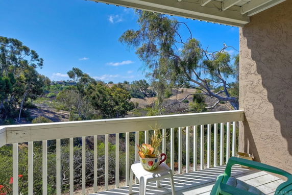 View from a balcony showing surrounding landscape with trees and distant buildings.