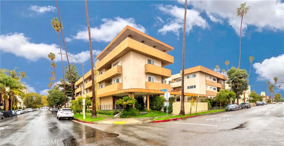 Front view of a multi-story apartment building on a street corner.