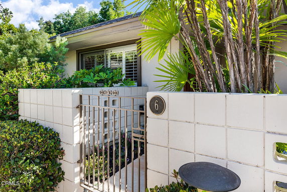 Front view of a house with a gated entrance and surrounding vegetation.