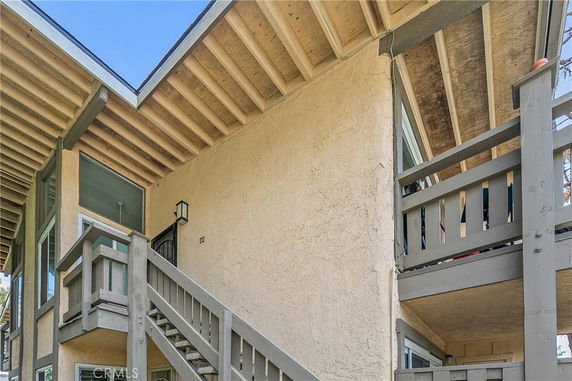 Side view of a two-story building with wooden railings and stairs.