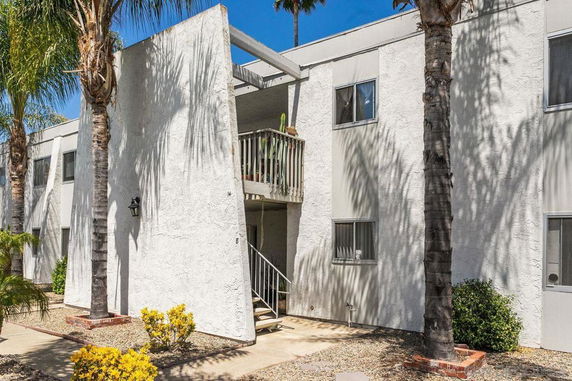 Front view of a two-story building with a stucco exterior and a central staircase.