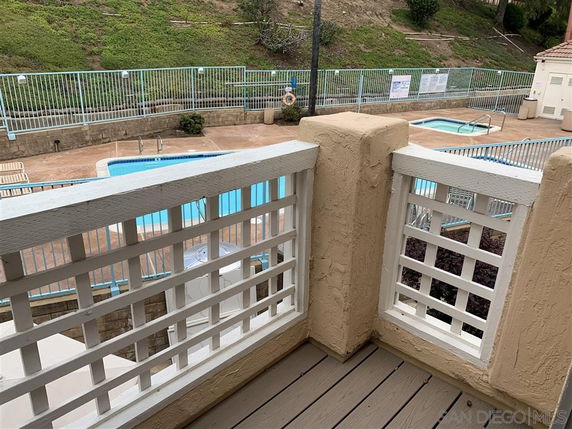 View from balcony overlooking a swimming pool area with fencing.